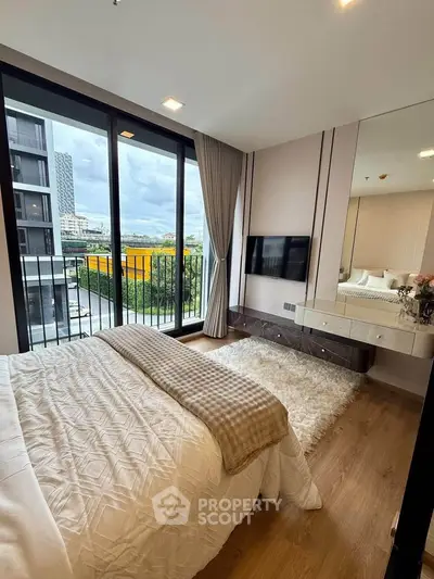 Modern bedroom with large windows and balcony access, featuring stylish decor and city views.