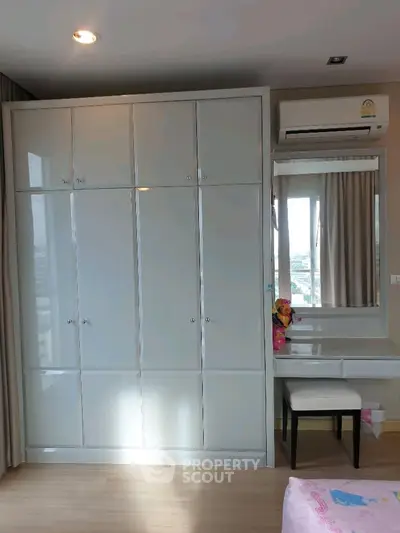Spacious bedroom with built-in wardrobe and vanity area, featuring modern design and ample storage.