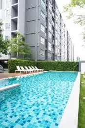 Modern apartment building with a sparkling outdoor pool and lush greenery.