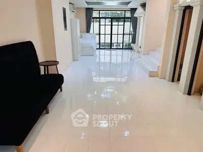 Spacious open-plan living area with glossy white tiles and modern furnishings.