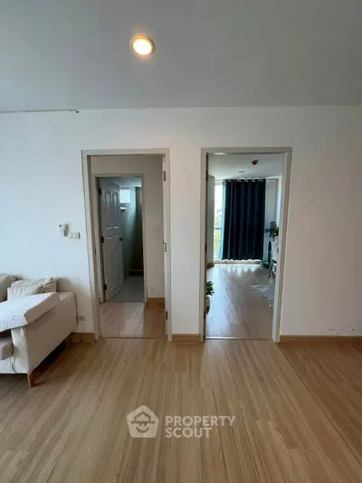 Spacious apartment interior with wooden flooring and modern decor, featuring a cozy living area and bright natural light.