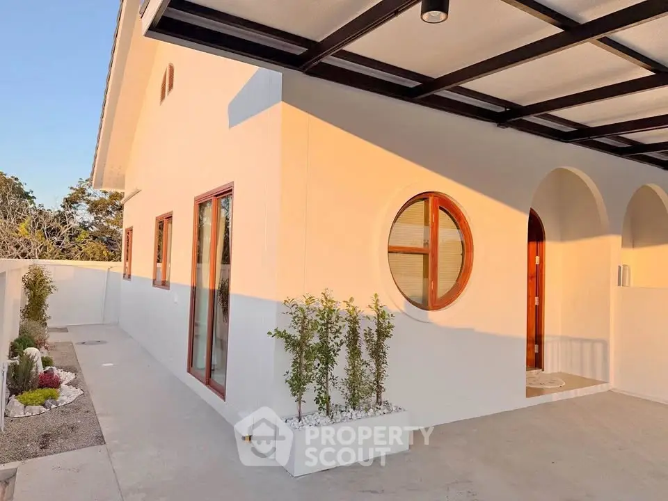 Modern white house exterior with unique circular window and minimalist landscaping.