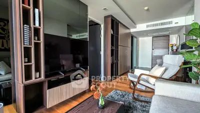 Modern living room with sleek furniture and stylish decor, featuring a large TV and cozy seating area.
