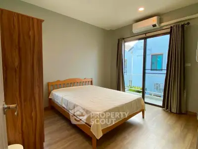 Spacious bedroom with wooden furniture and balcony access in modern apartment.