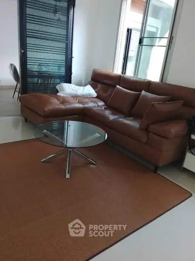 Modern living room with stylish brown leather sofa and glass coffee table
