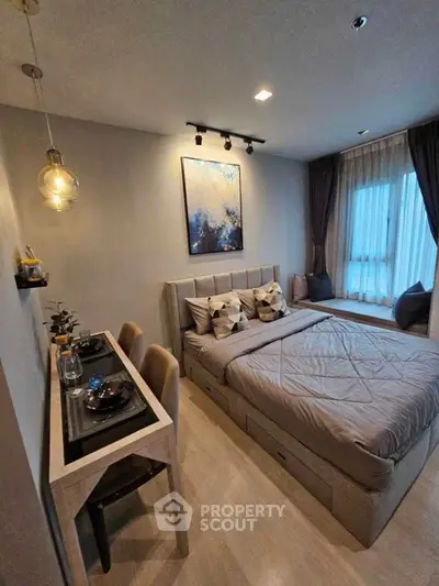 Modern bedroom with stylish decor and natural light, featuring a cozy bed and elegant dining area.