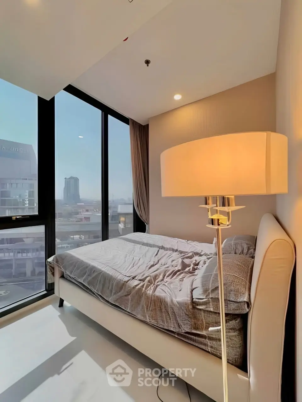 Modern bedroom with floor-to-ceiling windows offering stunning city views.