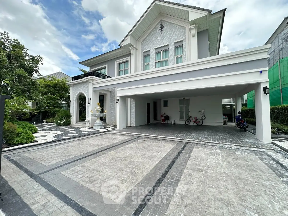 Elegant two-story house with spacious driveway and lush garden, perfect for luxurious living.