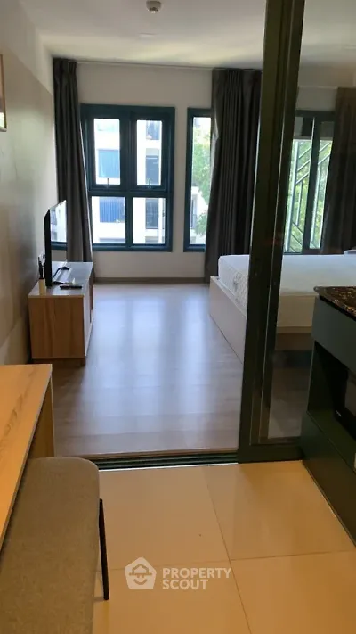 Modern studio apartment with open layout and large windows offering natural light.