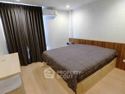 Modern bedroom with wooden flooring and large bed in a cozy apartment.