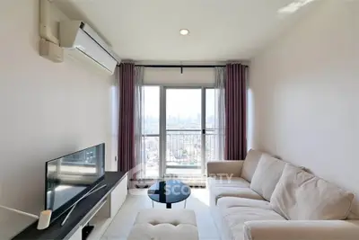 Modern living room with city view, featuring a cozy sofa and sleek TV setup.