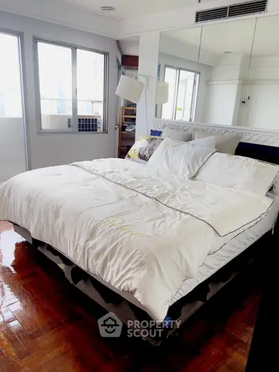 Spacious bedroom with large bed and mirrored wall in modern apartment