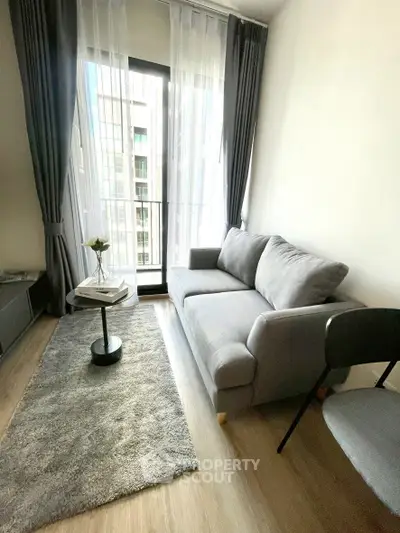 Modern living room with gray sofa and floor-to-ceiling windows in a stylish apartment.