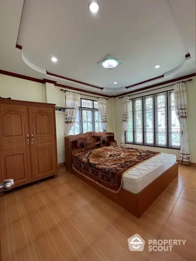 Spacious bedroom with wooden furniture and large windows for natural light.