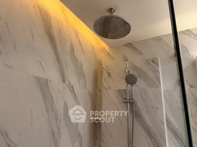 Luxurious marble bathroom with modern rain shower and ambient lighting.