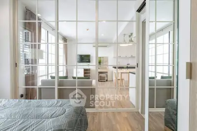 Modern open-plan apartment with glass partition, stylish living room, and sleek kitchen design.