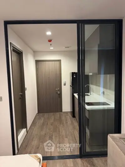 Modern compact kitchen with sleek design and glass sliding door in urban apartment.