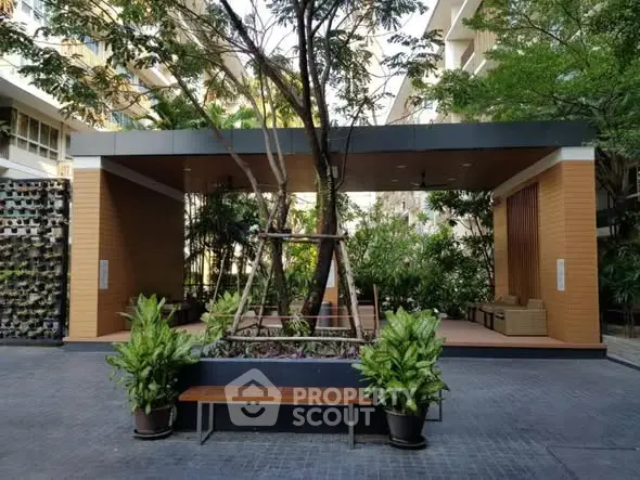 Modern apartment building entrance with lush greenery and seating area
