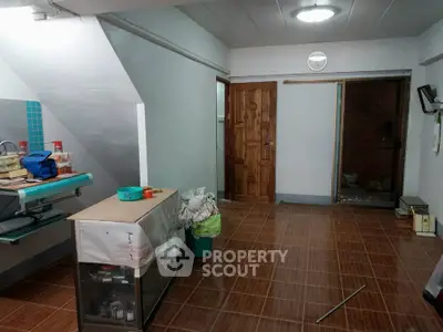 Spacious interior with tiled flooring and wooden door, ideal for versatile use.