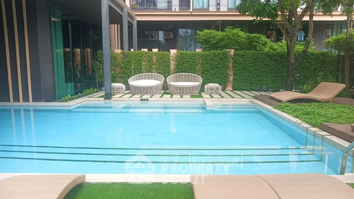 Luxurious residential pool area with stylish seating and lush greenery, perfect for relaxation and leisure.