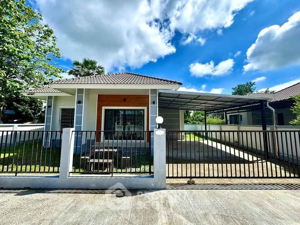 Charming single-story house with spacious driveway and lush greenery under a bright blue sky.