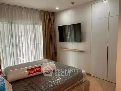 Modern bedroom with wall-mounted TV and large window for natural light.
