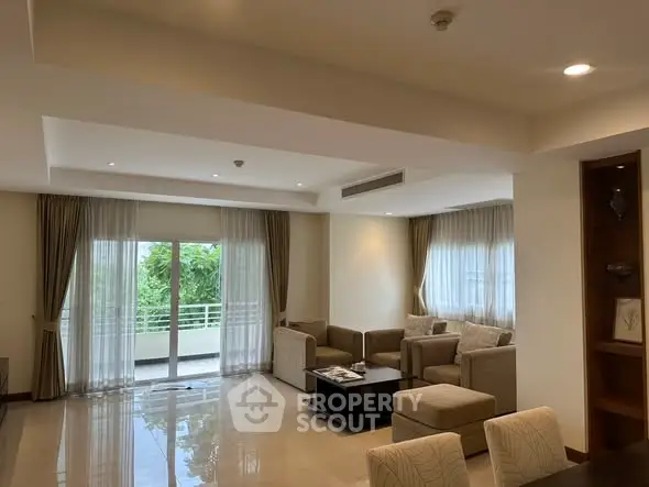 Spacious living room with elegant decor and large windows offering natural light and garden view.