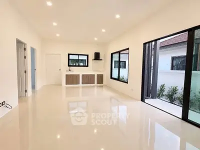 Spacious modern living room with large windows and sleek flooring, perfect for natural light and open living.