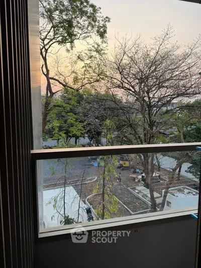 Scenic view from a window overlooking a serene outdoor area with trees and sunset.