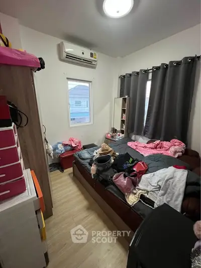 Cozy bedroom with air conditioning and natural light, featuring a comfortable bed and ample storage space.