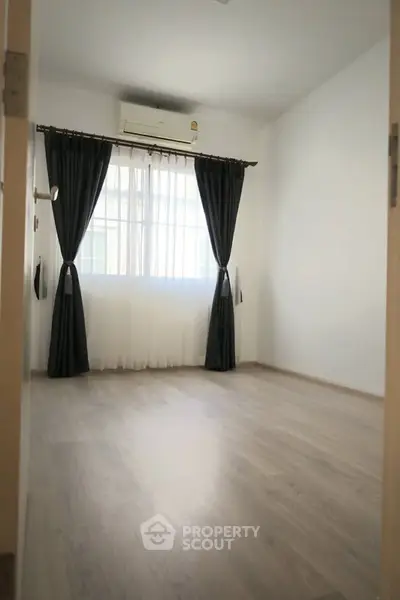 Spacious bedroom with elegant curtains and air conditioning, perfect for comfort and relaxation.