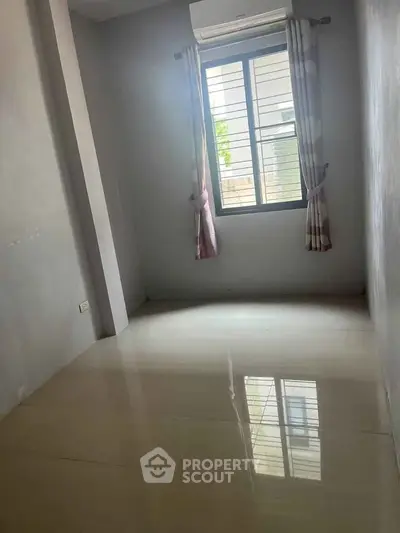 Spacious empty room with large window and polished floor, perfect for customization.