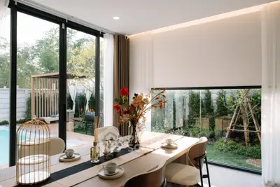 Elegant dining area with garden and pool view, featuring modern decor and large windows for natural light.