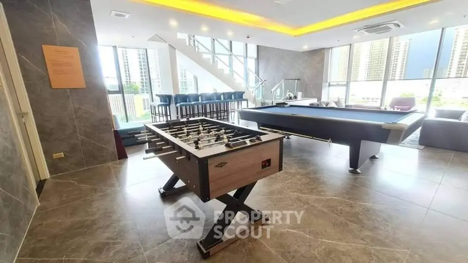 Luxurious game room with foosball and pool table, modern design, and city view in upscale apartment building.