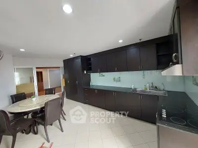Spacious kitchen with dark wood cabinets and dining area in modern apartment