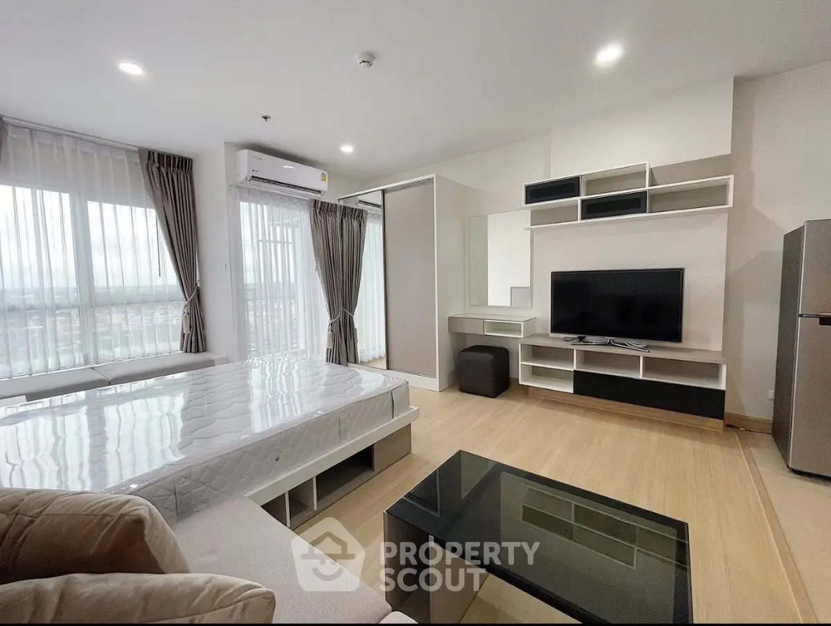 Modern studio apartment with large windows and stylish furnishings