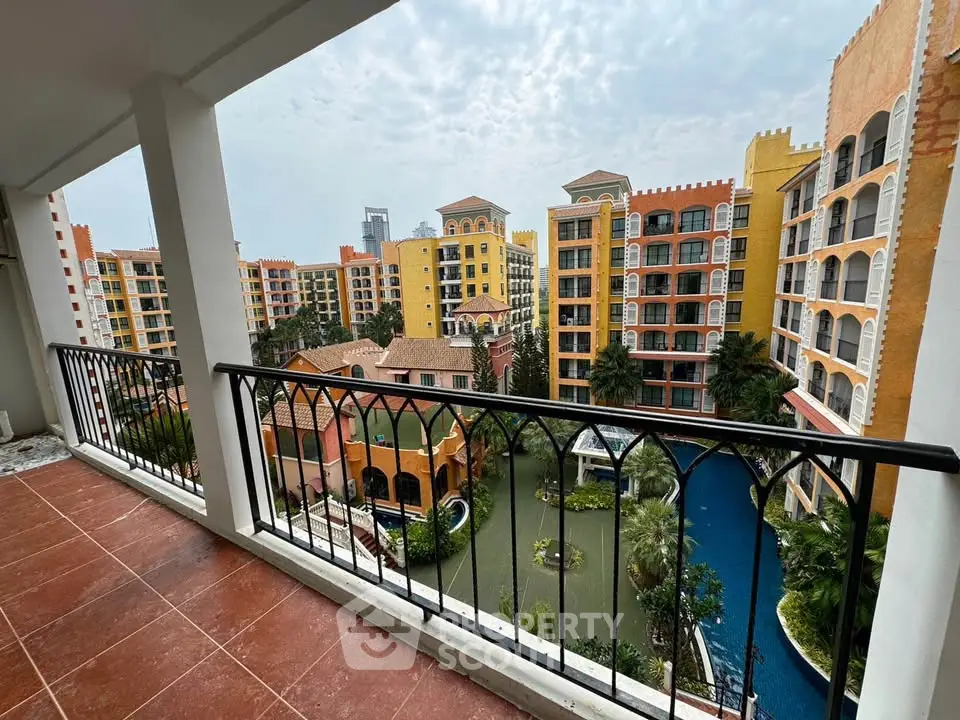 Stunning balcony view of colorful resort-style apartment complex with lush gardens and pool.