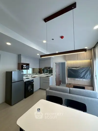 Modern open-plan kitchen and living area with sleek appliances and stylish lighting.