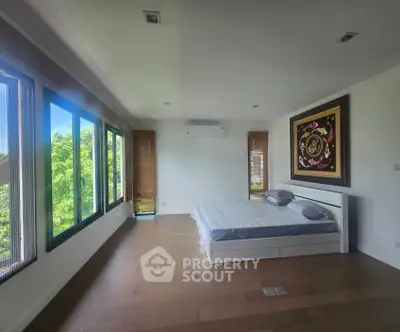 Spacious bedroom with large windows and modern decor, offering serene views and abundant natural light.