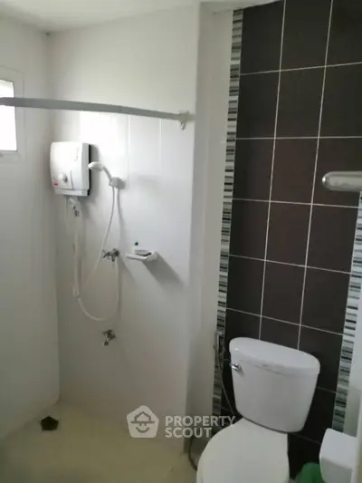 Modern bathroom with shower and toilet in a sleek, tiled design.