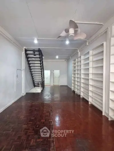 Spacious interior with wooden flooring and built-in shelves, ideal for storage or retail space.