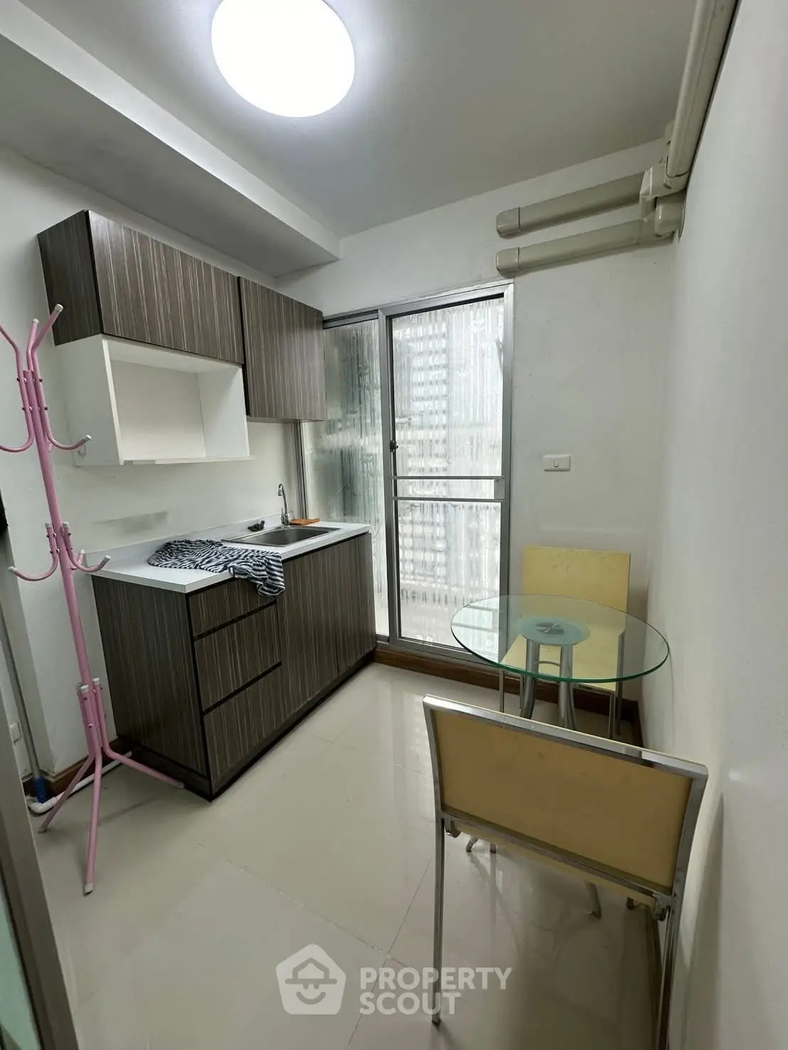 Compact kitchen with modern cabinetry and glass dining table in cozy apartment.