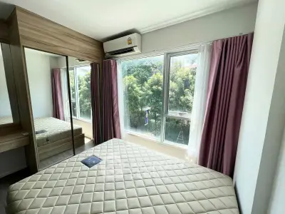 Bright bedroom with large windows and mirrored wardrobe, offering a serene garden view.