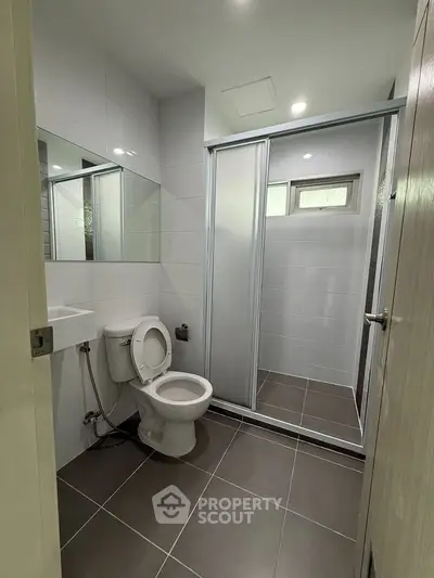 Modern bathroom with sleek design, featuring a glass shower enclosure and contemporary fixtures.