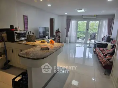 Spacious open-plan living room with modern kitchen and balcony view