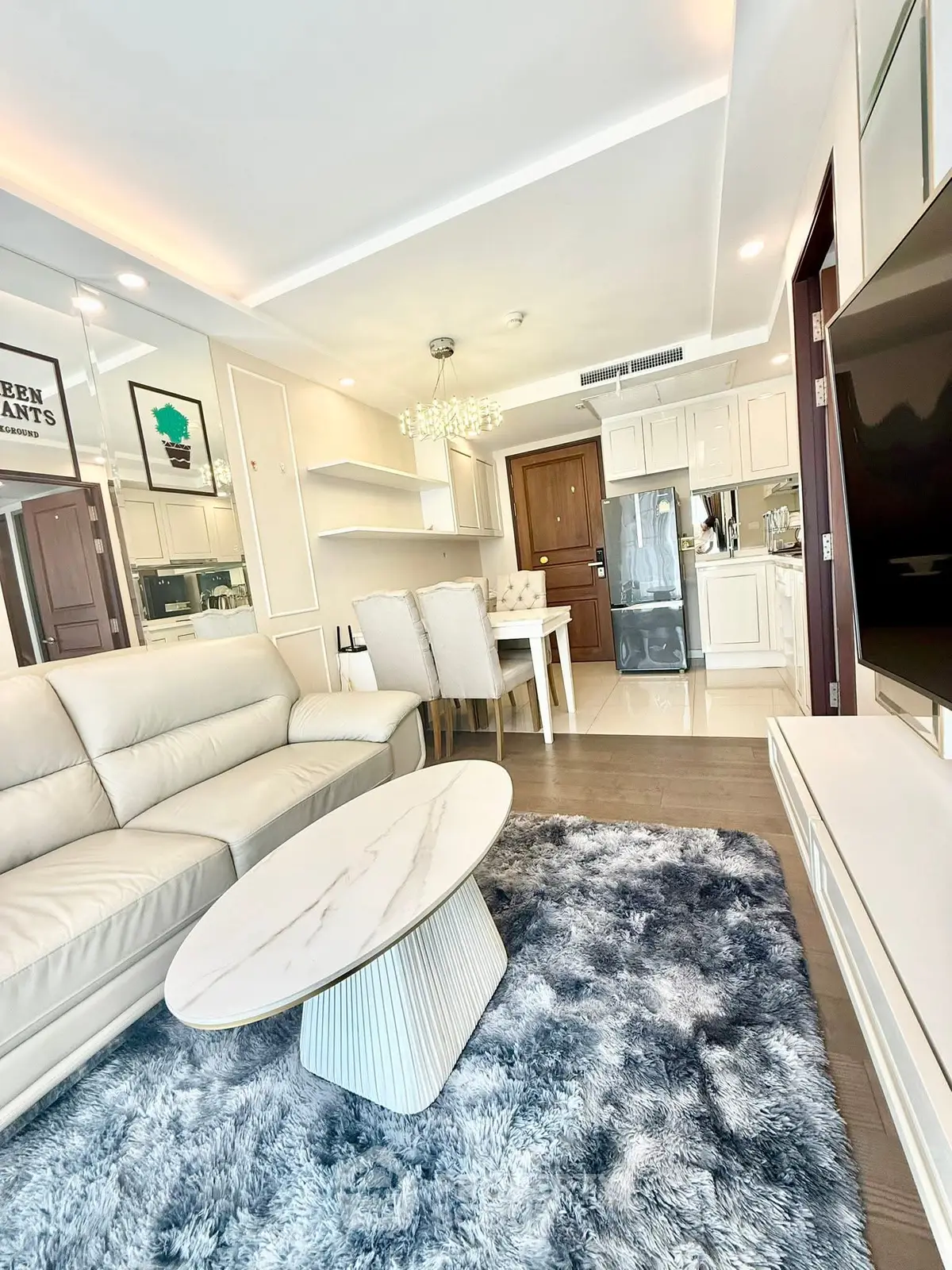 Luxurious living room with modern decor and open dining area, featuring plush sofa and elegant lighting.