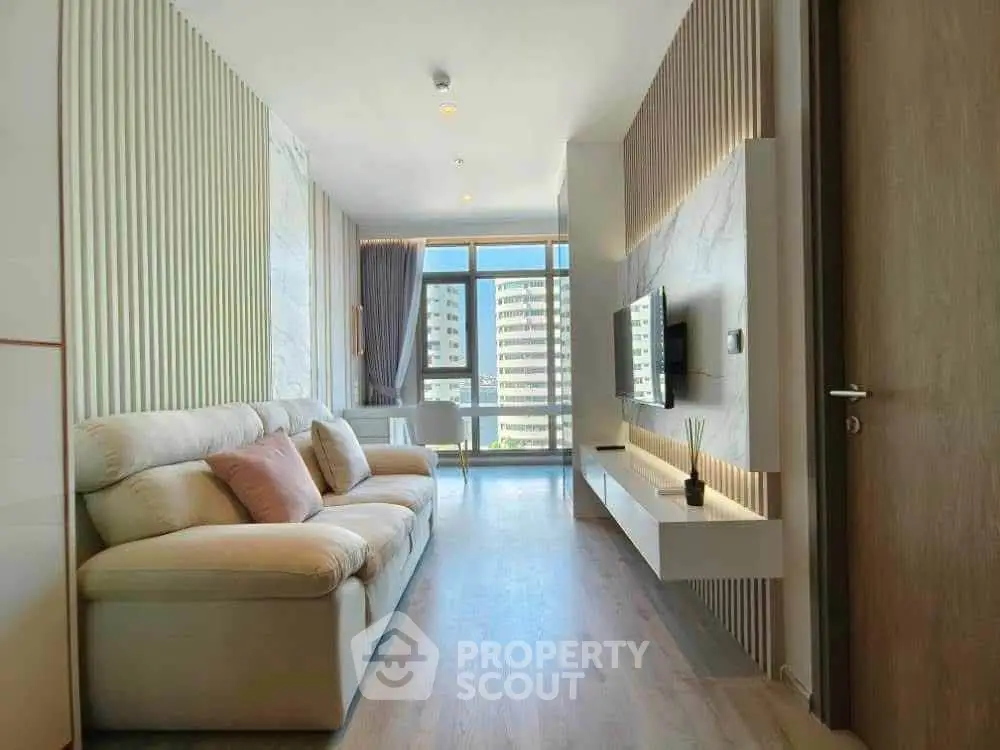 Modern living room with stylish decor and large windows offering city views.