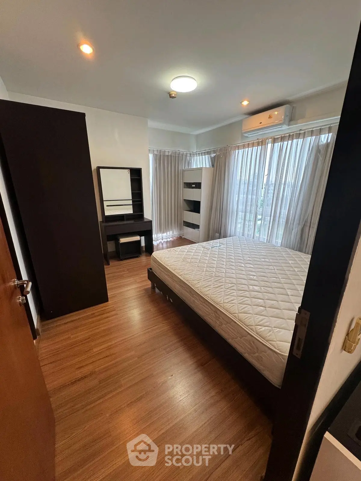 Spacious bedroom with large windows and modern furnishings, featuring a comfortable bed and ample natural light.