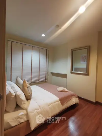 Cozy bedroom with wooden flooring and soft lighting, perfect for relaxation.