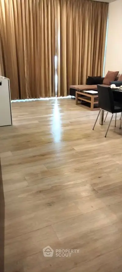 Spacious living room with wooden flooring and elegant curtains